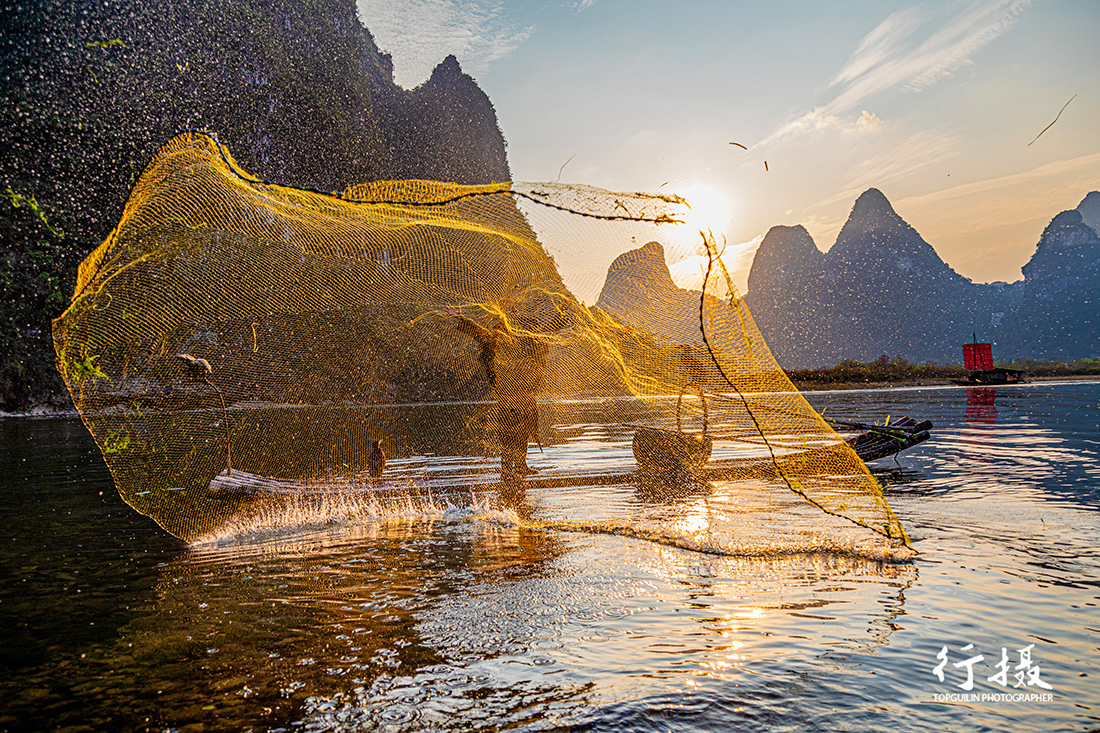 A fisherman on a bamboo raft beneath karst peaks at Xingping at sunset