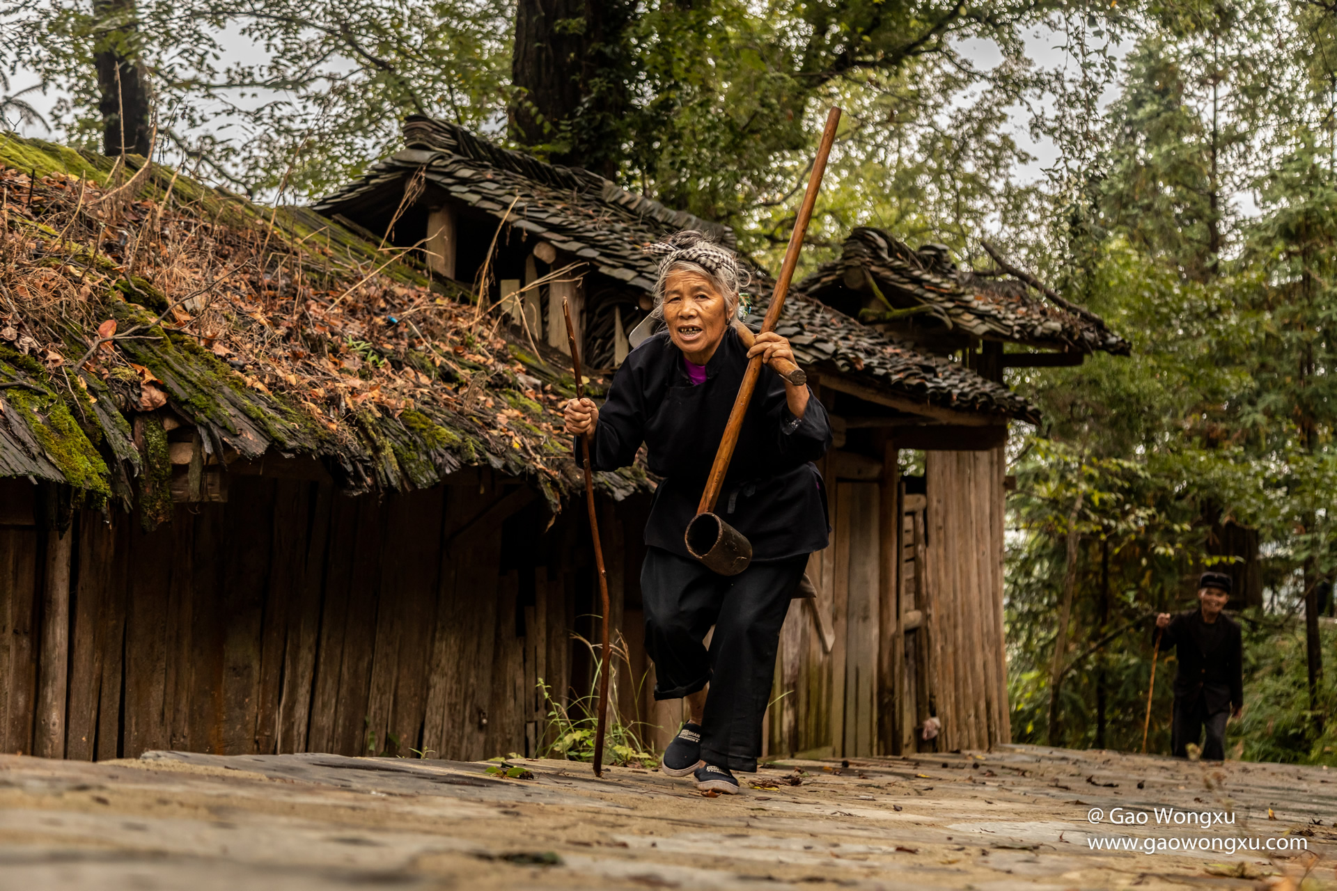 A Dong elder seated at the doorway of a timber house in Zhaoxing