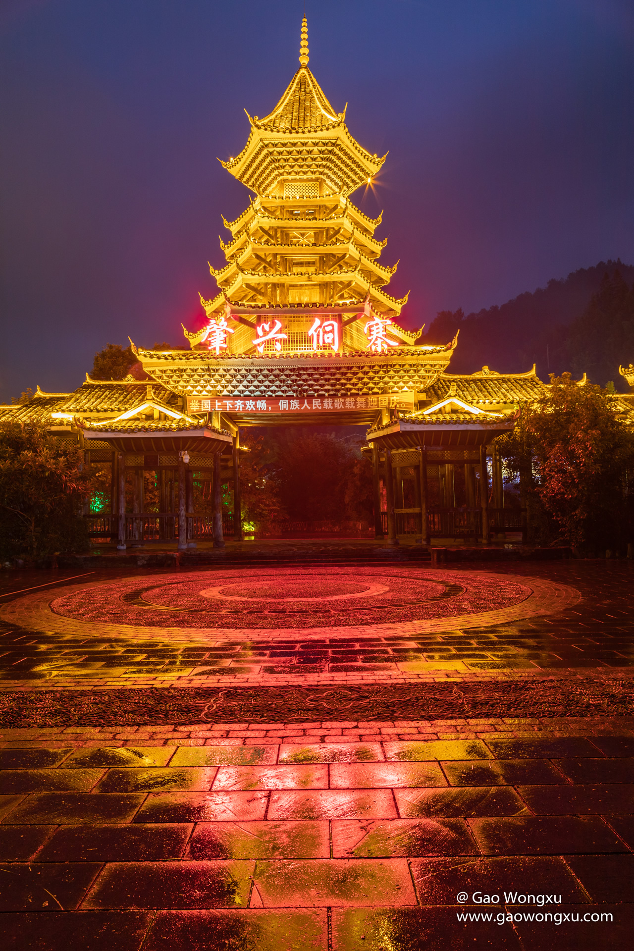 A multi-tiered Dong drum tower in Zhaoxing lit from within at night