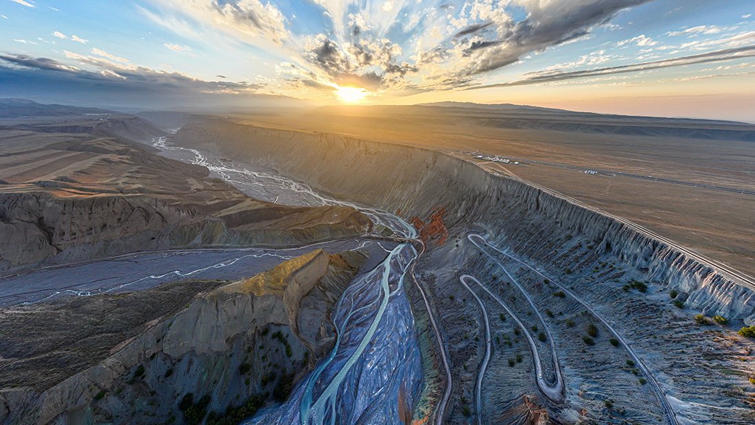 Backlit cliffs of Anjihai Grand Canyon glowing at sunset over the braided river