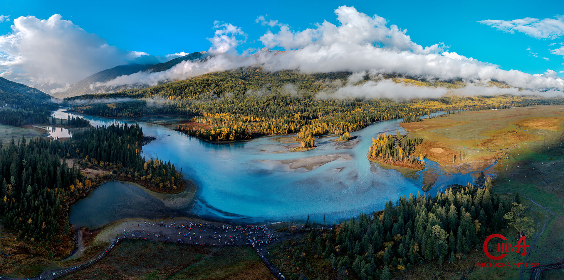 Broad Kanas river valley with cloud shadow drifting over forested mountain ridges