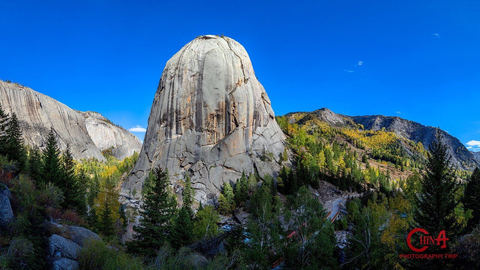 Shenzhong Mountain, the great granite dome of Koktokai, above autumn larch forest