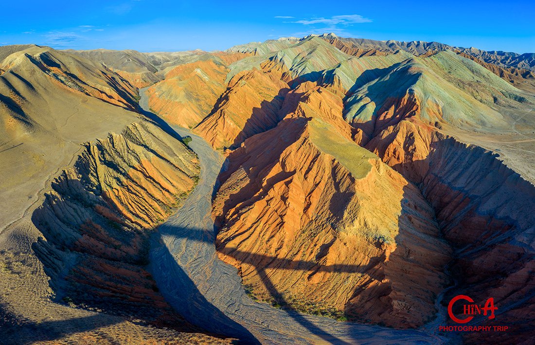 Rainbow-banded strata hills of the S101 Danxia belt under warm afternoon light