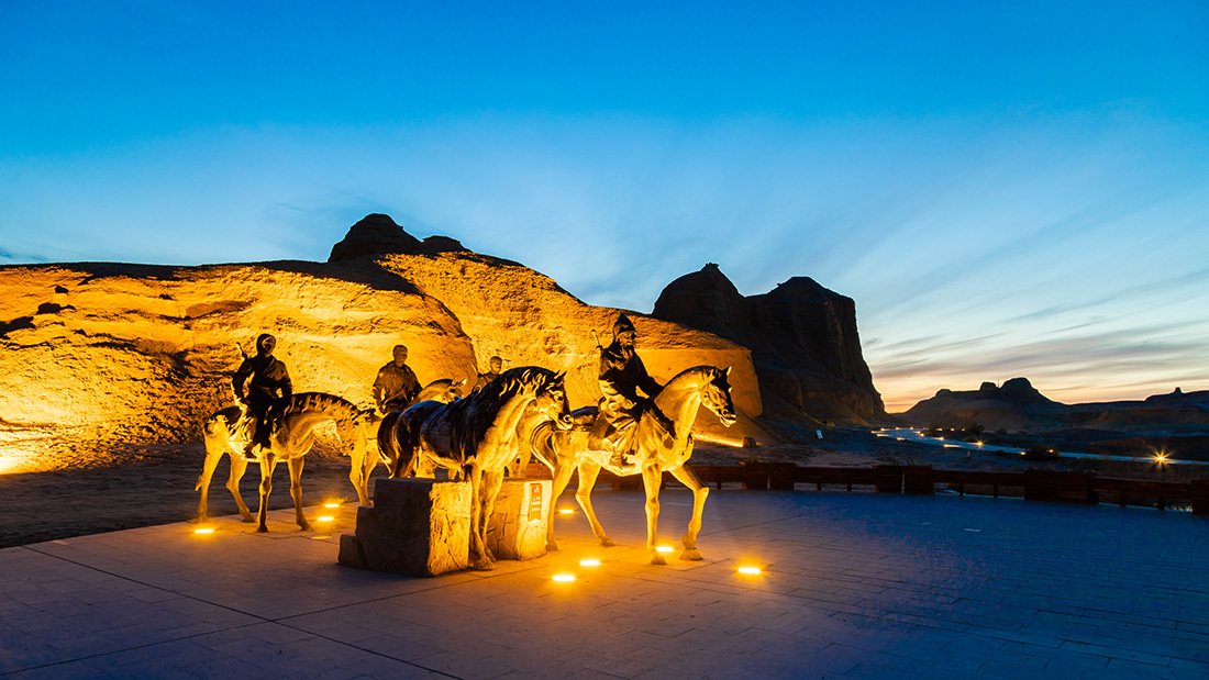 Camel silhouettes crossing the yardang formations of Urho Ghost City at dusk