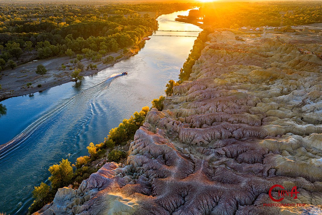 Aerial view of the multicoloured Wucaitan cliffs and the Irtysh River in golden-hour light