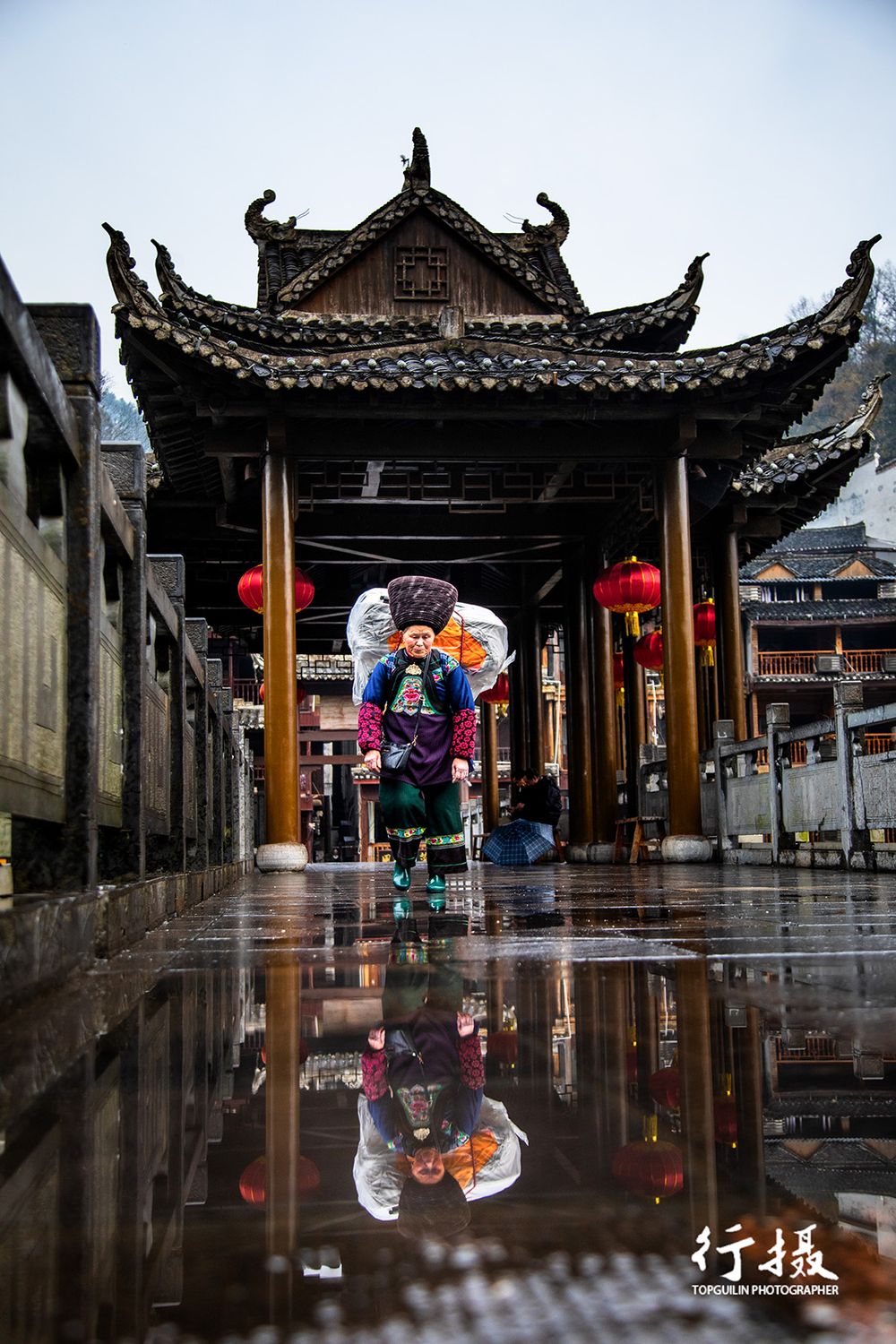 A woman walking through a lantern-hung street in Fenghuang old town at night