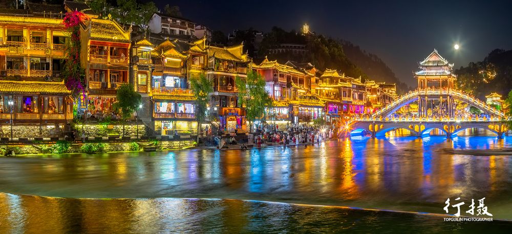 Lantern-lit stilt houses along the Tuo River waterfront in Fenghuang at night